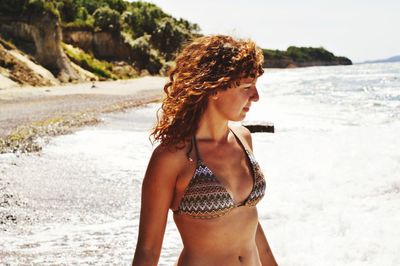 Beautiful woman standing on beach against sky