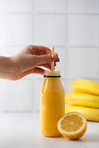 Yellow smoothie in a bottle with a straw, lemon and bananas. the concept of healthy eating.