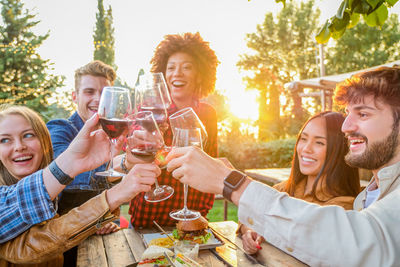 Smiling friends toasting drinks on table