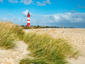 Lighthouse on beach against sky