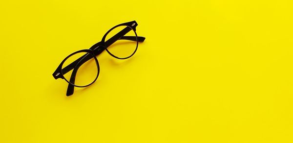 High angle view of eyeglasses against yellow background