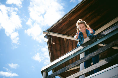 Low angle view portrait of woman standing at observation point against sky