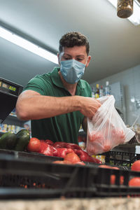 A fruit seller with a mask taking fruit from a box