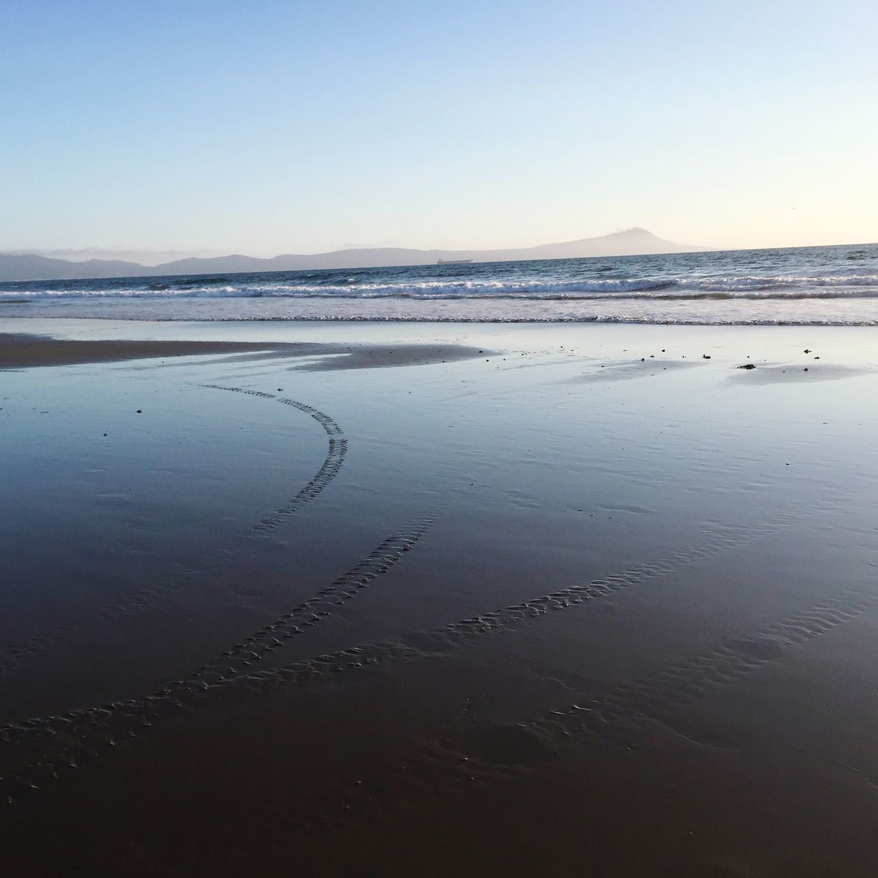 beach, water, scenics, tranquil scene, tranquility, sea, clear sky, beauty in nature, sand, vacations, tourism, copy space, travel destinations, reflection, shore, blue, nature, non-urban scene, coastline, distant, mountain, sky, seascape, outdoors, majestic, tide, wave, no people, horizon