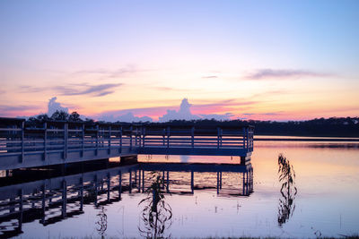 Pier over lake against sky during sunset