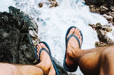 Low section of man in flip-flops against river stream