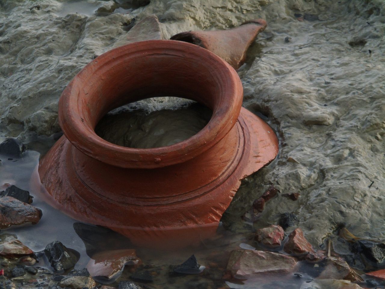 no people, high angle view, solid, day, orange color, nature, close-up, water, rock, shape, rock - object, outdoors, pottery, geometric shape, clay, brown, metal, animal, circle, wheel