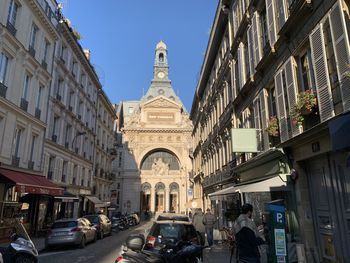 Cars on street amidst buildings against sky in city