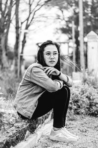 Portrait of young woman sitting on field