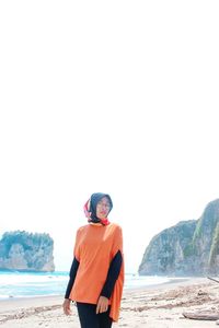 Woman in hijab standing at beach against clear sky