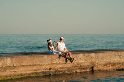 Dad and daughter in santa claus hats eat ice cream on the pier