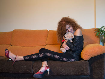 Woman with dog sitting on sofa at home