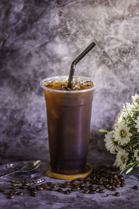 Thai coffee in a tall plastic cup there is steam next to the glass, cold.