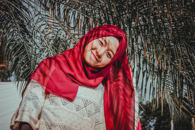 Portrait of smiling young woman wearing hijab against tree