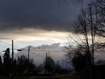 Silhouette trees and electricity pylon against sky