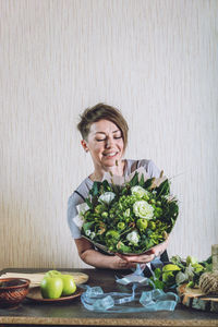 Young woman holding flower arrangement at home