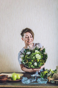 Young woman holding fruits in bowl on table