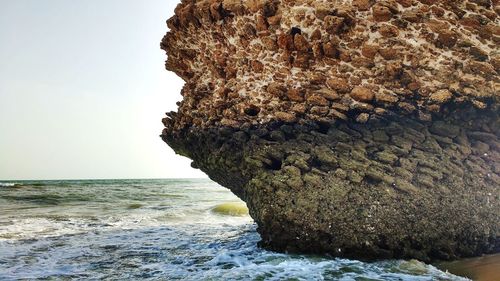 Rock formation by sea against clear sky