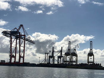 Cranes at commercial dock against sky