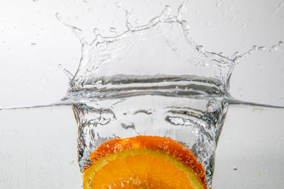 Close-up of water splashing on glass against white background