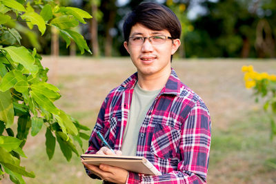 Portrait of young man holding plant