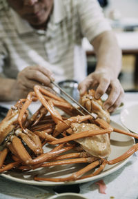 Close-up of hand holding meat in plate on table