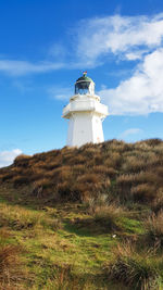 Lighthouse by sea against sky