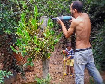 Full length of shirtless man working in yard