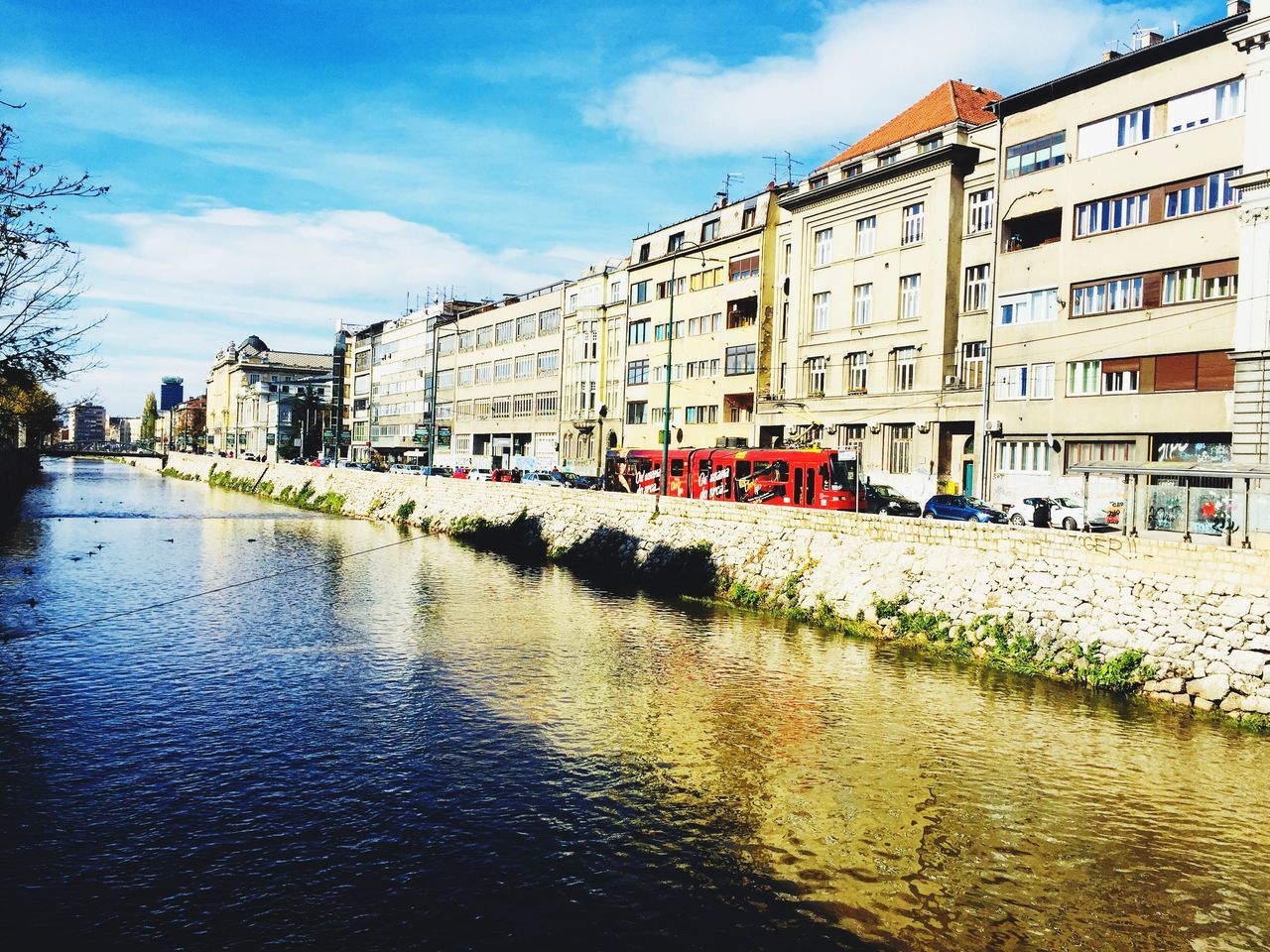 architecture, building exterior, built structure, sky, day, city, river, water, waterfront, bridge - man made structure, outdoors, mode of transport, cloud - sky, transportation, city life, large group of people, residential building, travel destinations, nautical vessel, nature, people