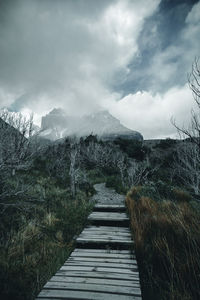 Footpath leading towards mountains against sky