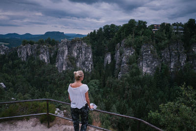Woman looking at mountain while standing by railing