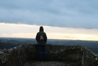 Rear view of people standing on mountain against sky