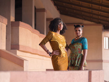 Portrait of female friends standing against house