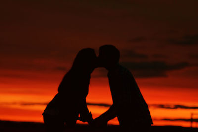 Silhouette couple against orange sunset sky