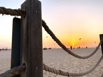 Wooden posts on beach against sky during sunset