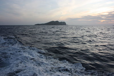 Islet or rocky cliff between the rough sea of ibiza and the blue sky in balearic islands