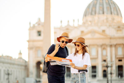 Happy tourists looking at a map and choose a hotel. couple of tourists on vacation in rome, italy. 