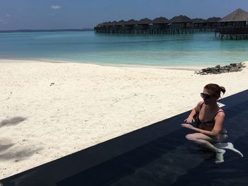 Portrait of woman sitting on beach against sky
