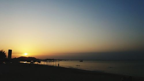 Scenic view of beach against clear sky during sunset