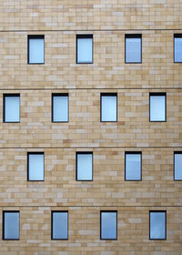 The facade of a modern stone building with geometric repeating pattern of small windows