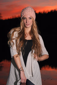 Portrait of beautiful young woman wearing hat against orange wall