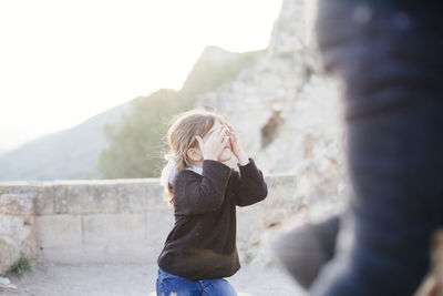 Young woman standing on rock against clear sky