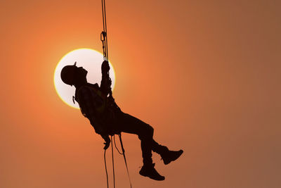 Silhouette man jumping against orange sky