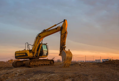 Excavator on earthworks at construction site on sunset background. backhoe digs ground 