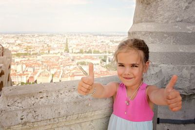 Smiling girl showing thumbs up outdoors