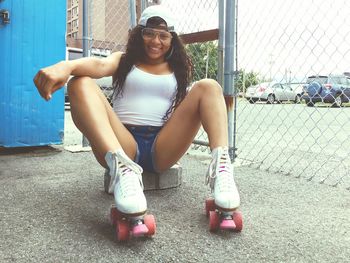 Portrait of young woman with roller skates sitting on rock