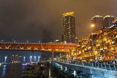 Illuminated bridge and buildings against sky at night