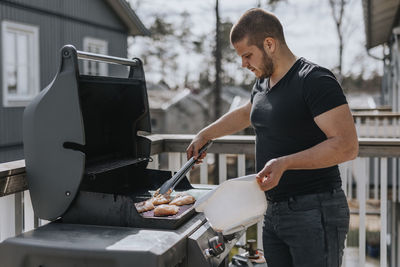 Man on balcony grilling chicken