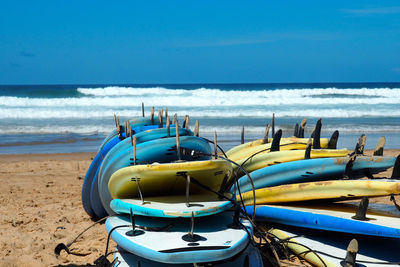 Surfboards on shore at beach against clear sky