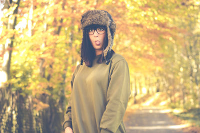 Young woman standing against trees